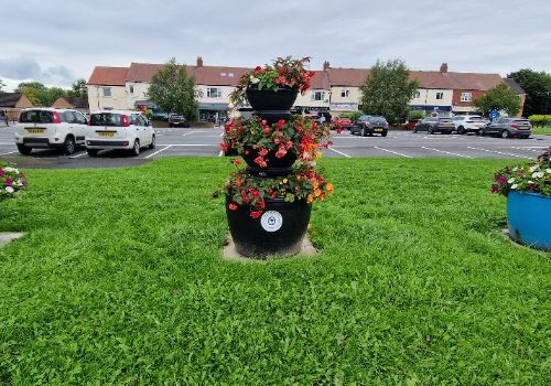 Flower pots on the green in front of Broadway shops in Colburn